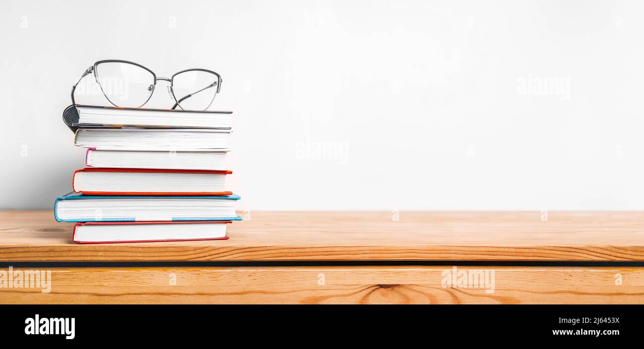 A stack of books and glasses on the table. Mock up with education and reading concept. Literature for learning, development and joy Stock Photo