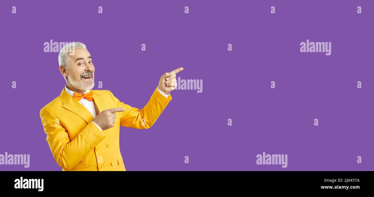 Handsome middle age man pointing away side with his finger isolated purple background. Spase for your advertisement. Stock Photo