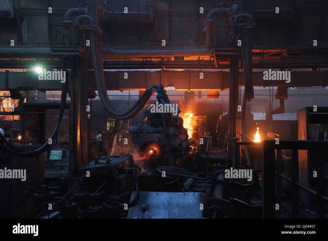 Production process of cast iron water pipes at industrial steel mill. Metallurgical foundry factory with press forming machines for manufacturing tubing. Heavy industry interior background. Stock Photo