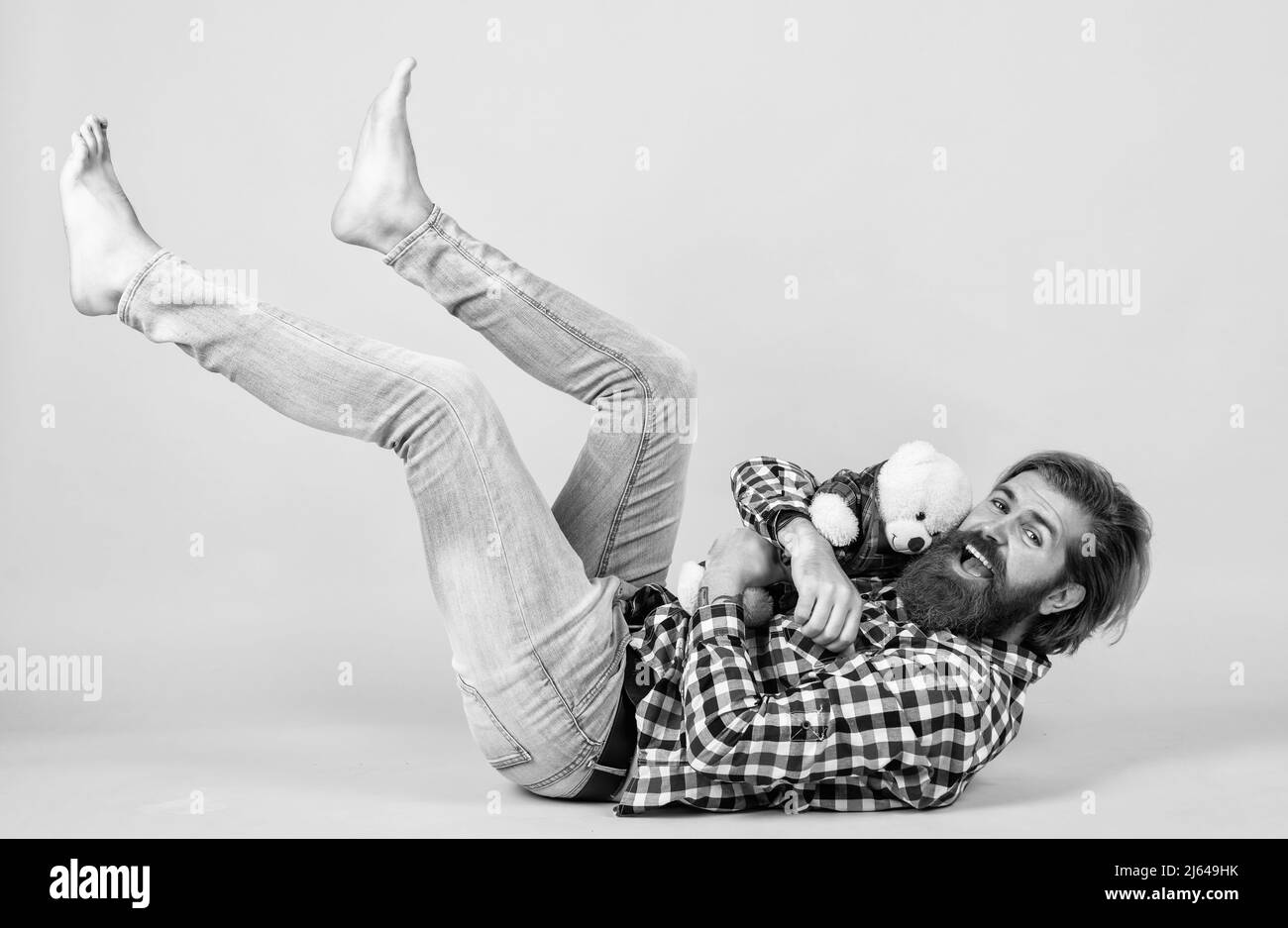 happy handsome bearded guy with unshaven face and stylish hairdo wear casual clothes and playing with bear toys, happiness Stock Photo