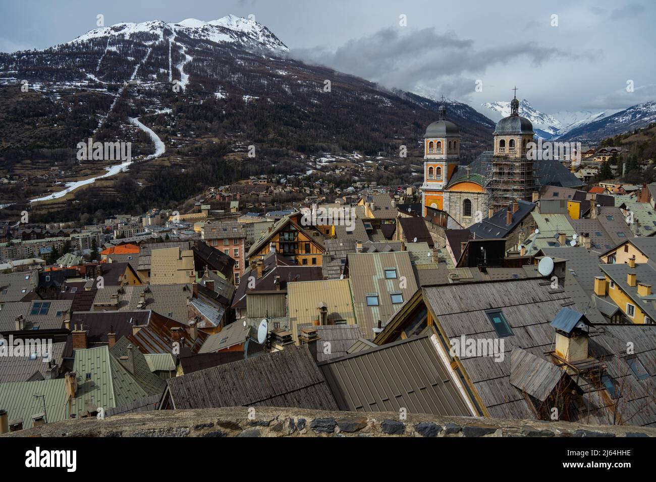Briancon, France - 15 Mar 2022: View of Briancon from above with the Collegiate Church of Our Lady and Saint Nicholas and the Alps in the background Stock Photo