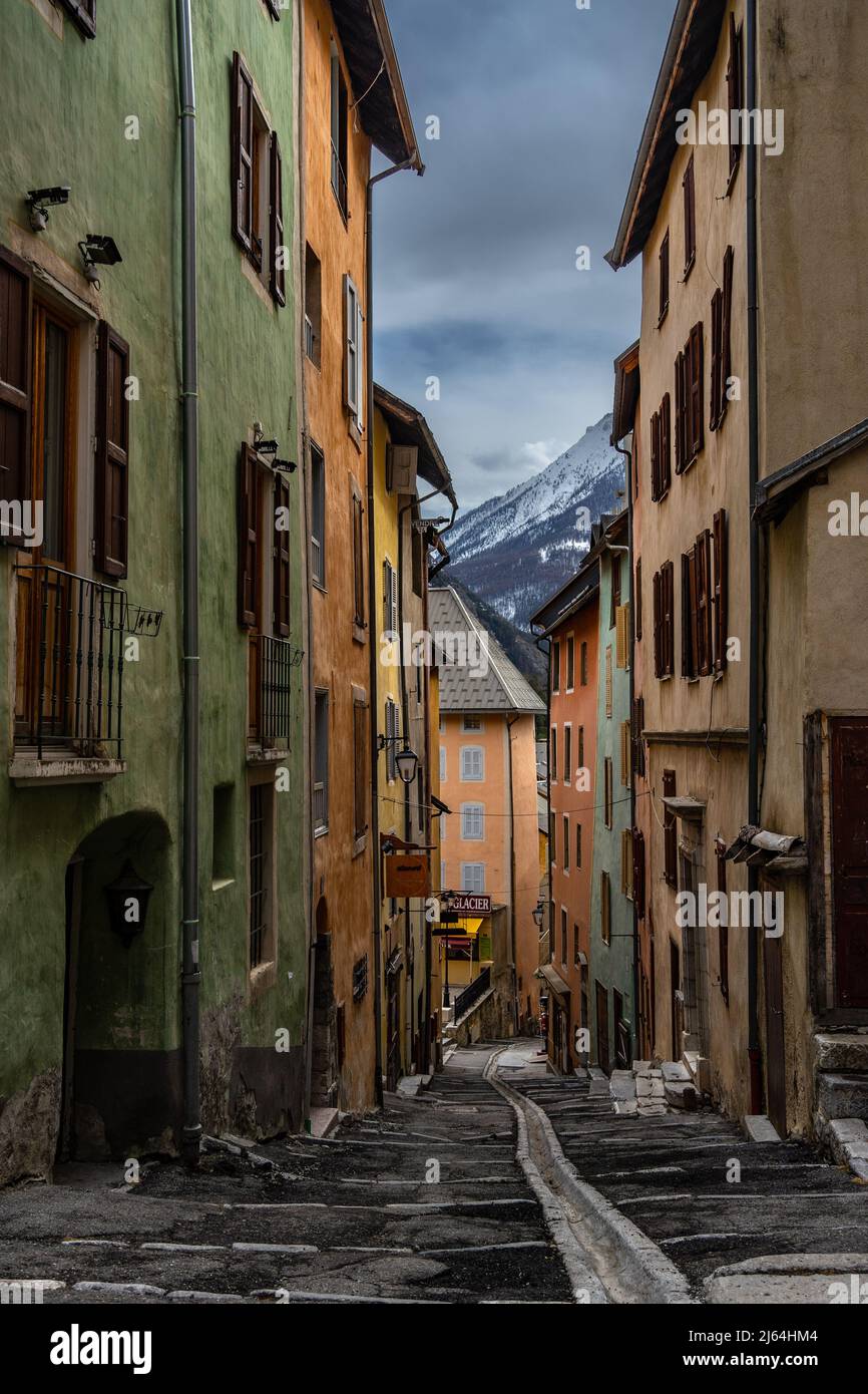 Briancon, France - 15 Mar 2022: Colorful medieval street of Briancon with a view of the snowy mountains; most beautiful streets in the world wallpaper Stock Photo