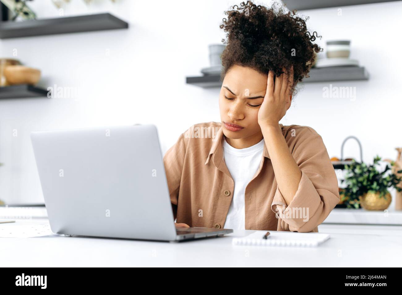 Exhausted afro-american girl, freelancer or student, working or study remotely from home, tired of boring online work, suffering from chronic fatigue, overwork, falls asleep at workplace, closed eyes Stock Photo