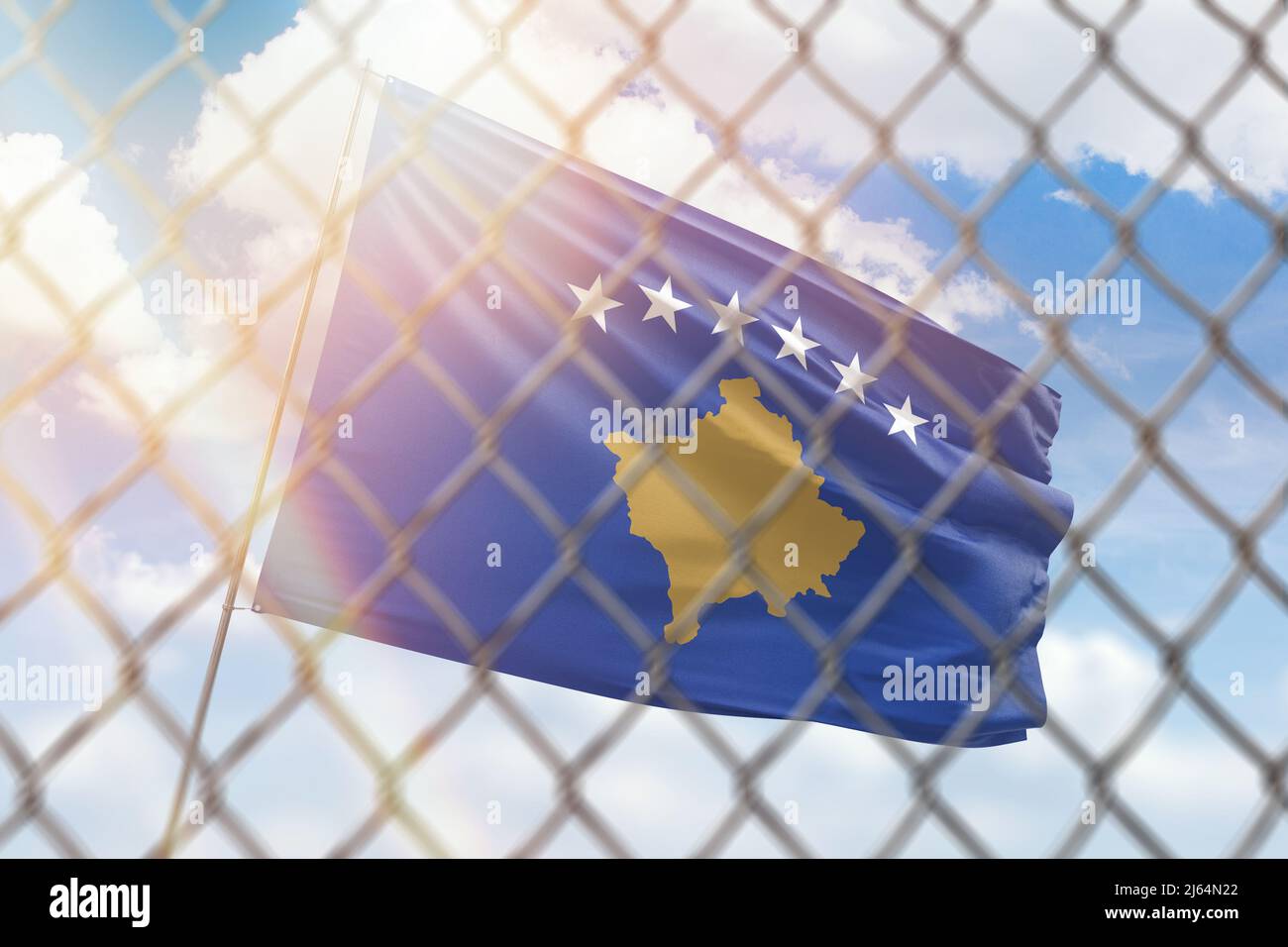 A steel mesh against the background of a blue sky and a flagpole with the flag of kosovo Stock Photo