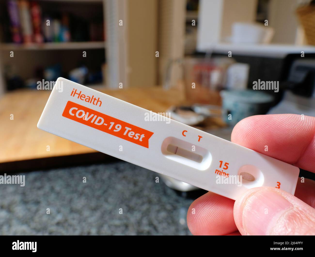 Person's hand holding an iHealth COVID-19 Antigen Rapid Test in-home self test card displaying a negative Coronavirus result; at home. Stock Photo