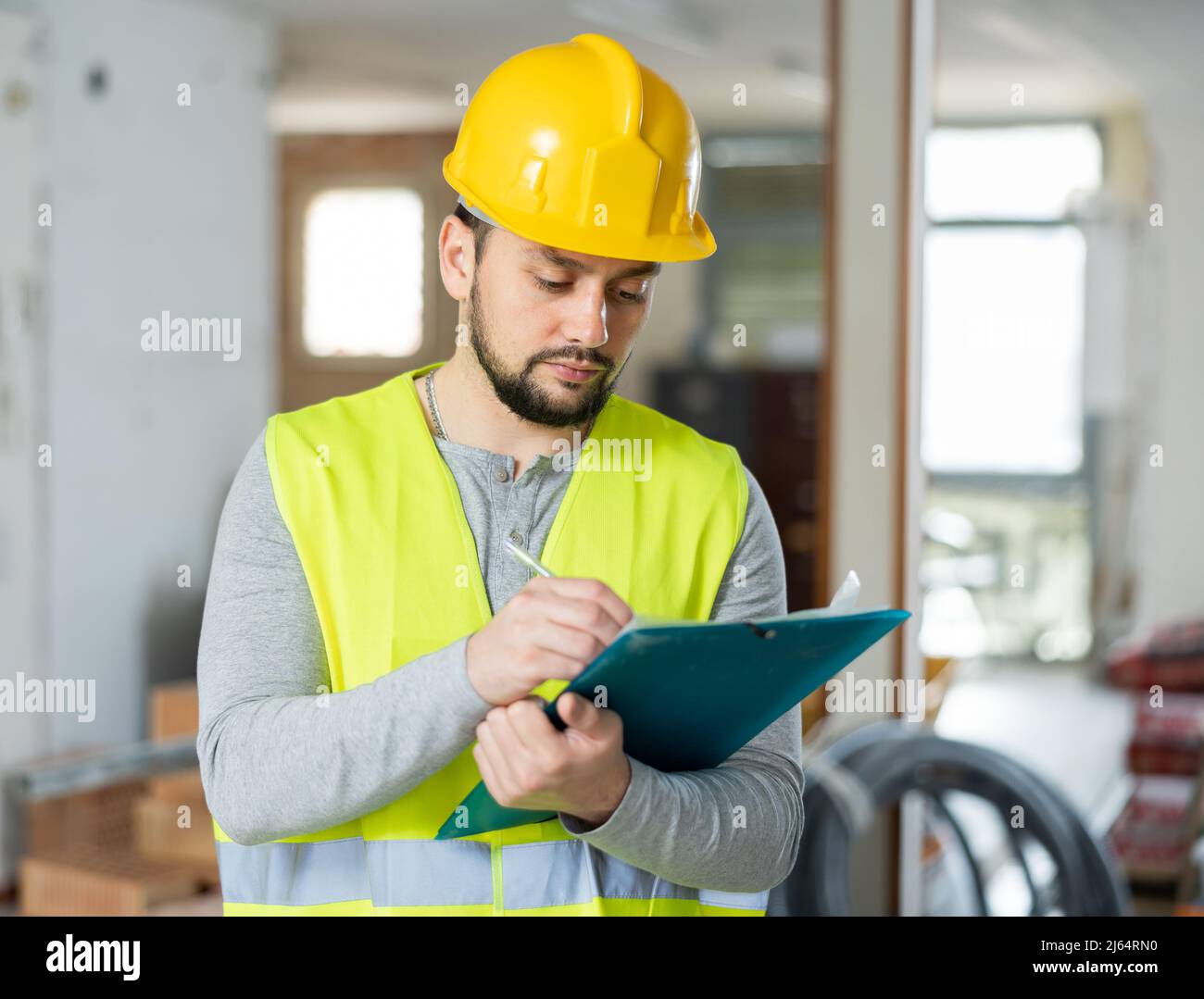 Builder making notes on indoor construction site Stock Photo