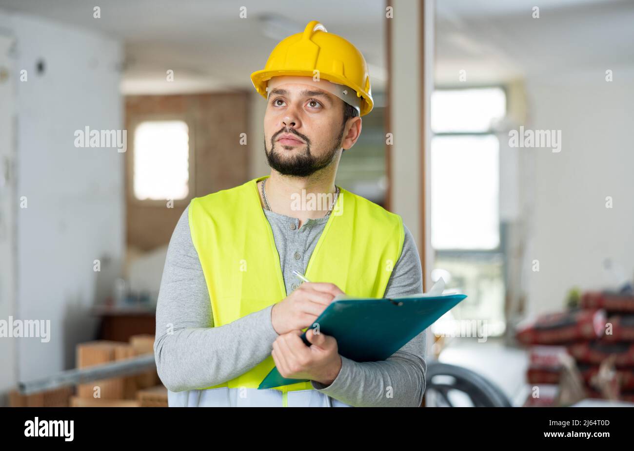 Focused supervisor taking notes while inspecting construction site Stock Photo