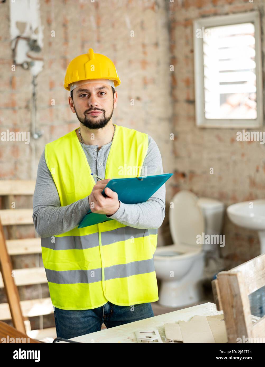 Builder making notes on indoor construction site Stock Photo