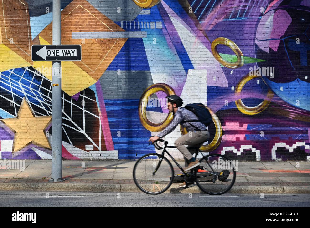 A commuter rids his bike past a mural on Wilmington Street in downtown Raleigh, North Carolina. Stock Photo