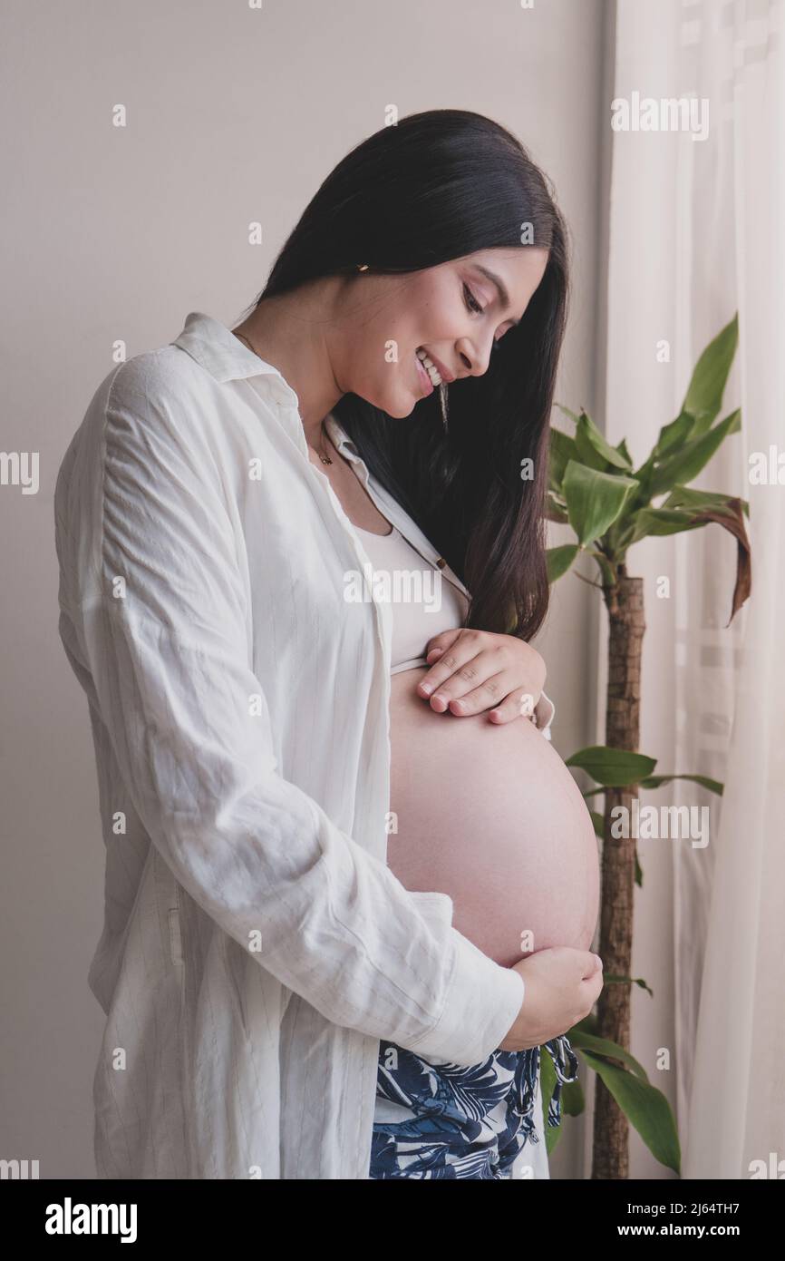 Pregnant mother holding her belly with her hands and feeling the baby's kicks Stock Photo