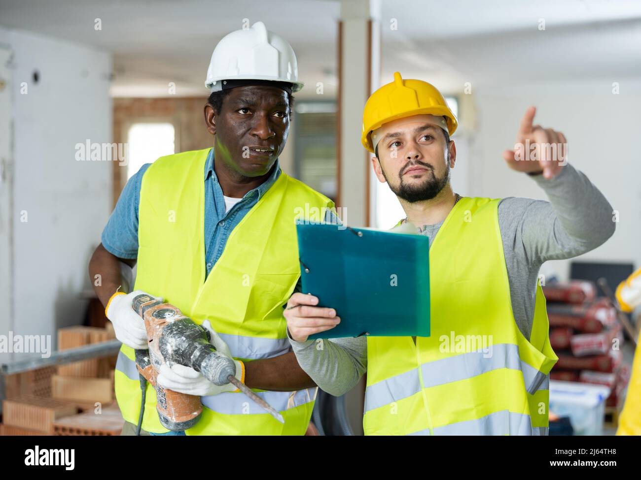 Two builders talking on indoor construction site Stock Photo