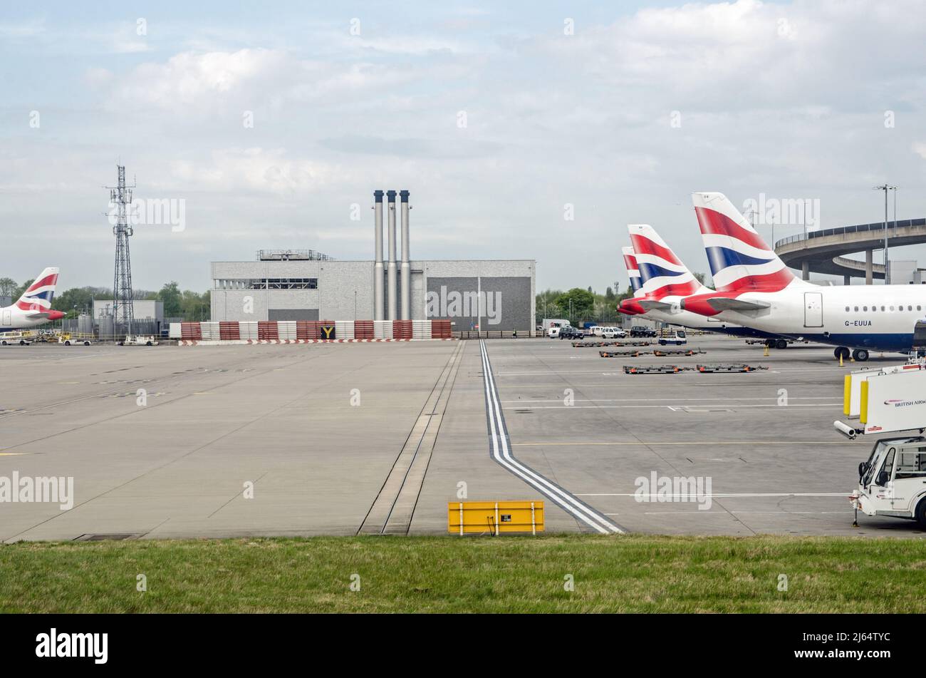 London, UK - April 19, 2022: View of an industrial support building complete with chimneys next to the main Terminal 5 buildings with British Airways Stock Photo