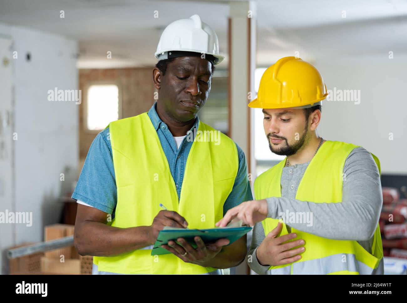 Two builders talking on indoor construction site Stock Photo