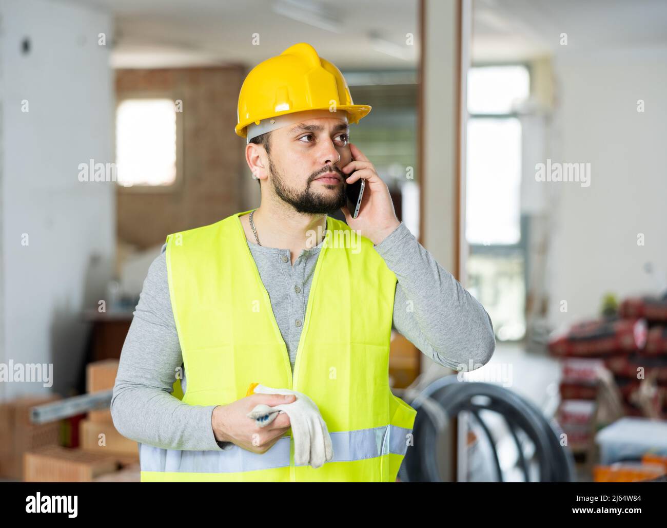 Young bearded civil engineer talking on phone at construction site Stock Photo
