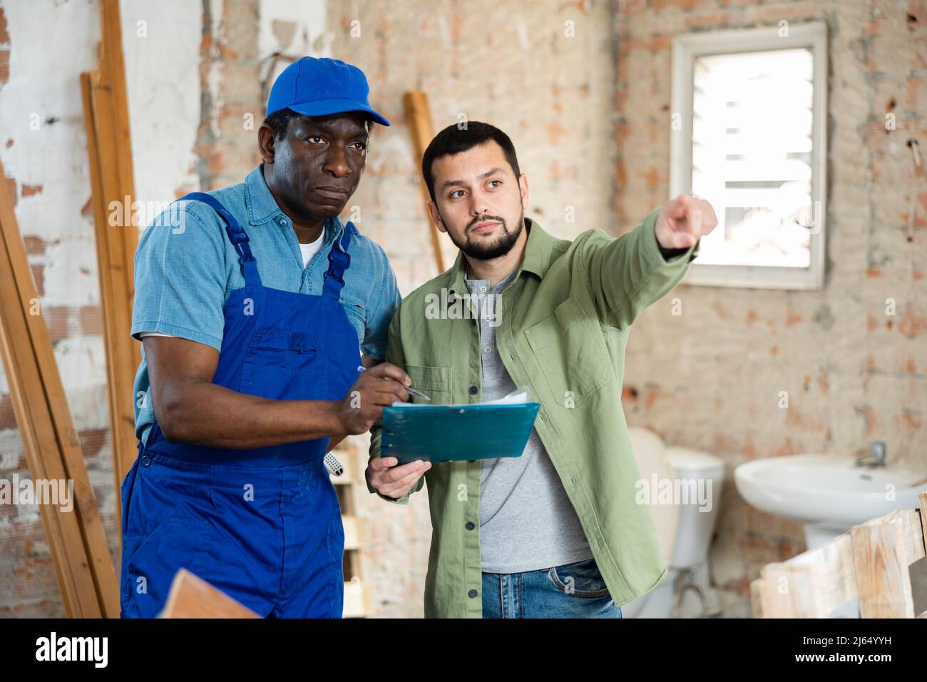 Builder having conversation with designer about working plan Stock Photo
