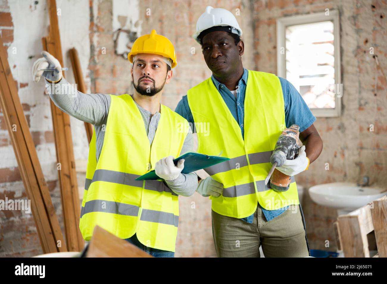 Two builders talking on indoor construction site Stock Photo