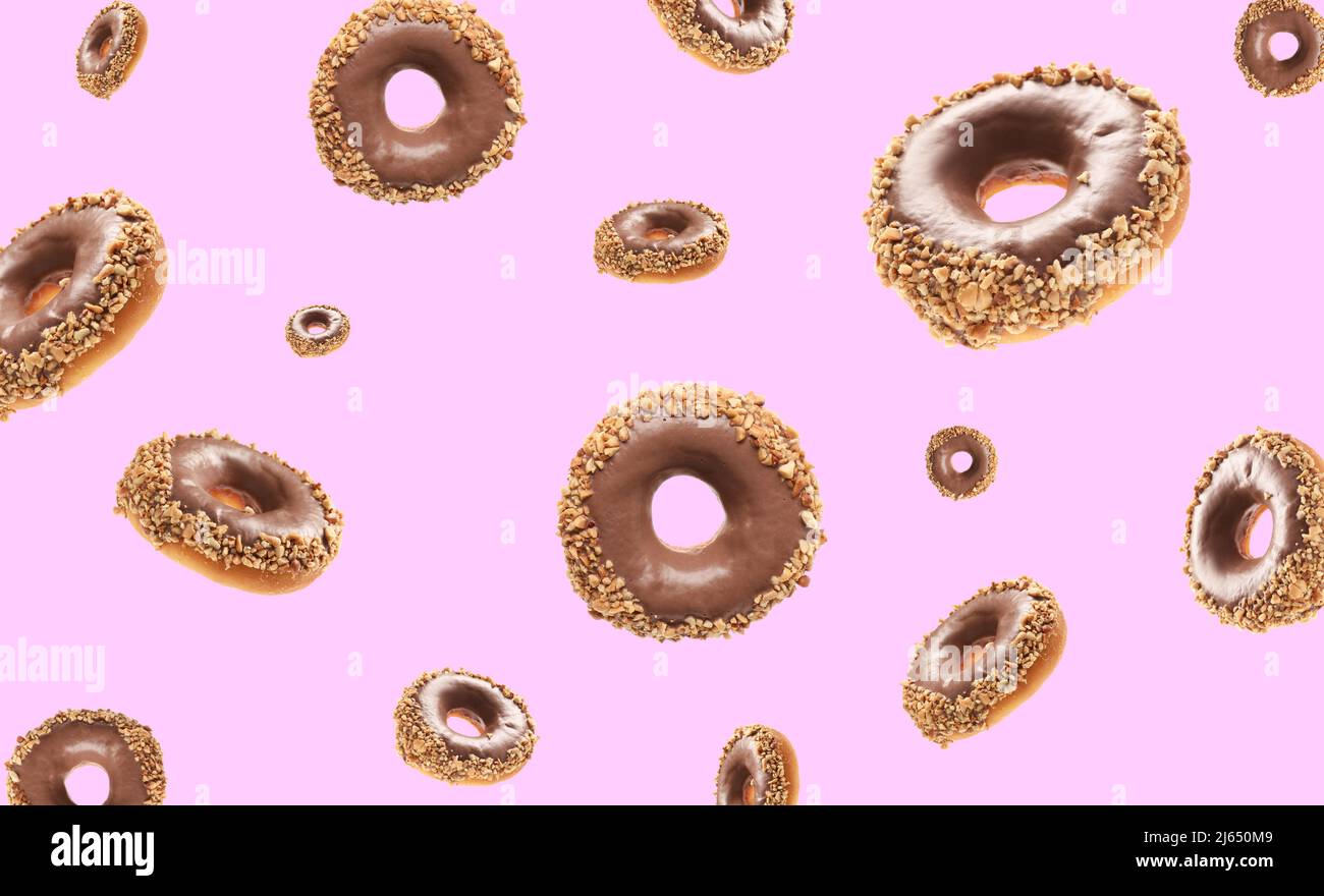 Many flying chocolate donuts on pink background Stock Photo