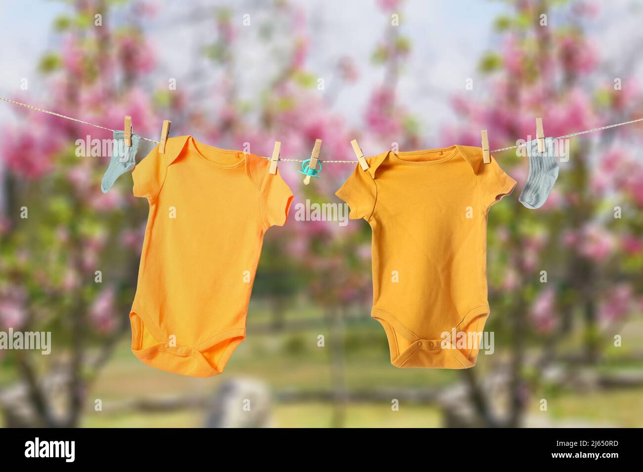 Yellow baby clothes hanging on rope outdoors on spring day Stock Photo ...
