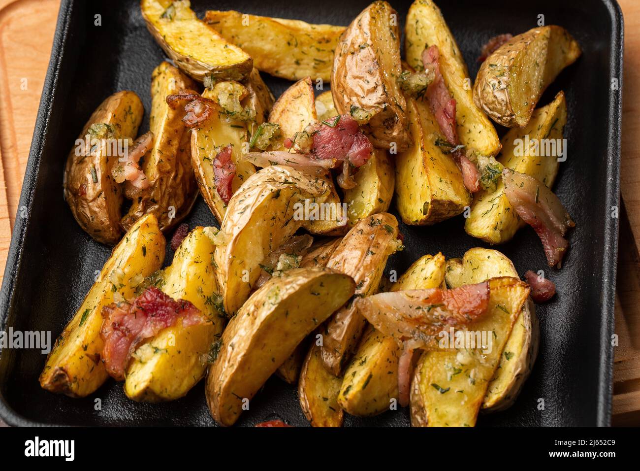 Delicious Fried Potato Bratkartoffeln With Bacon and Onion close up in the black plate on the table Stock Photo