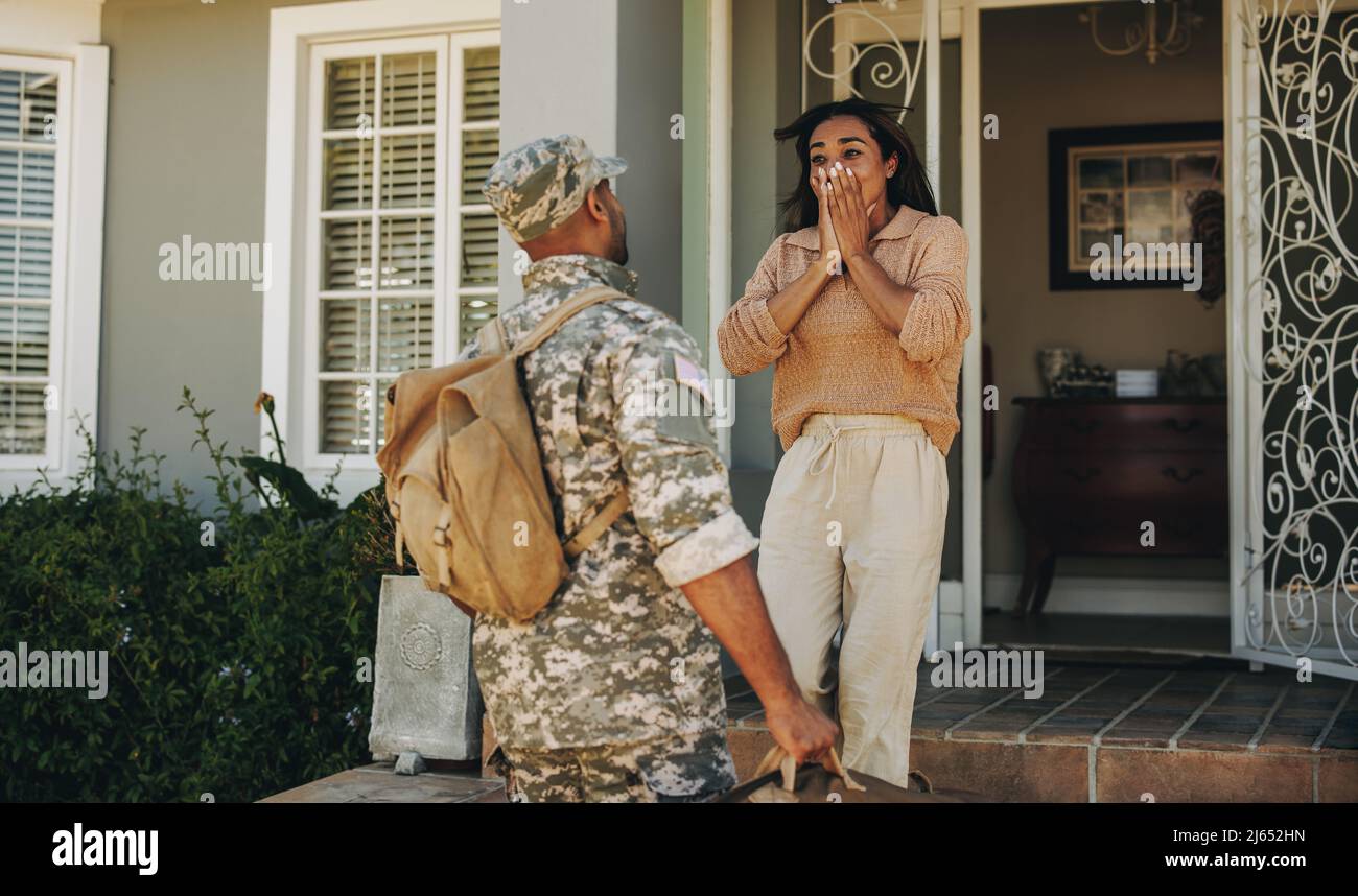 Patriotic young soldier surprising his wife with his homecoming. Courageous young serviceman reuniting with his wife after serving his country in the Stock Photo
