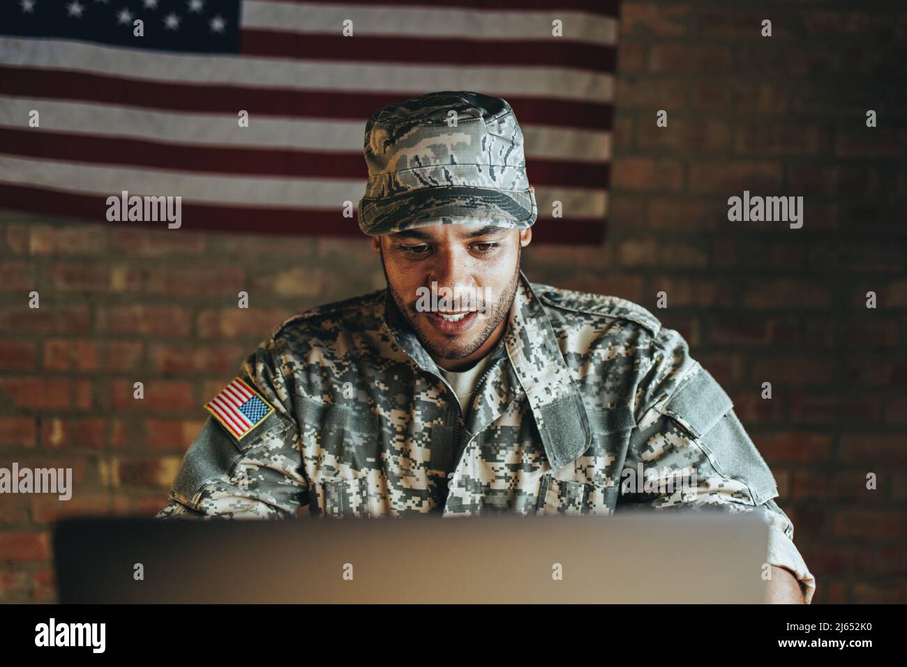 Patriotic young soldier video calling his family from the military base. Courageous American serviceman communicating with his loved ones while servin Stock Photo