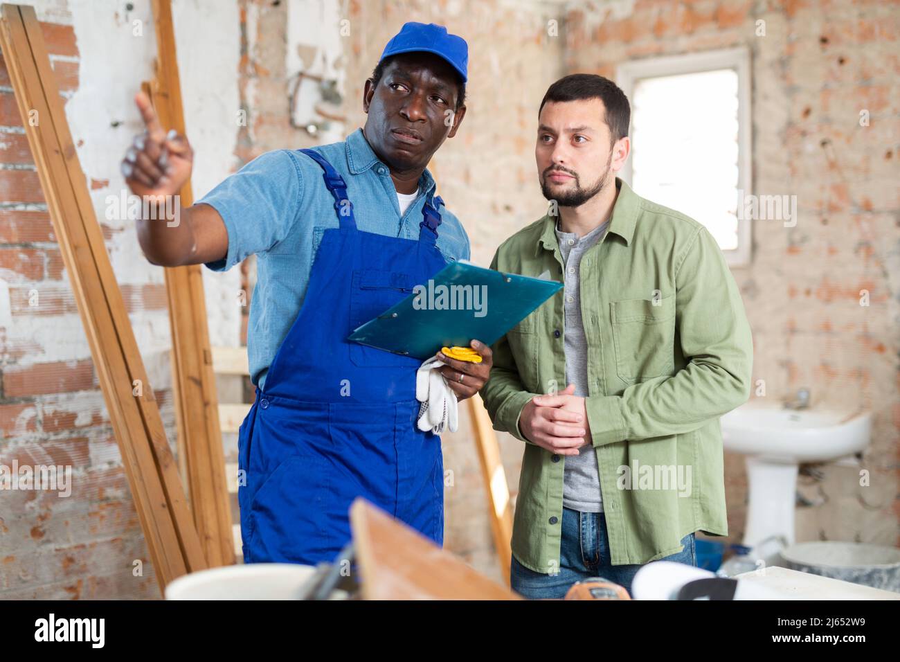Builder having conversation with designer about working plan Stock Photo