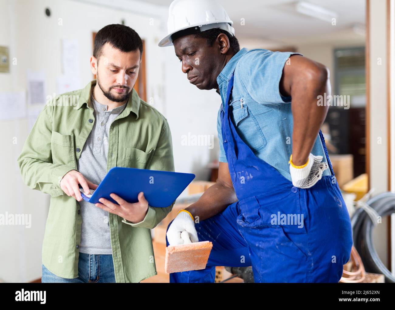 Two men talking on indoor construction site Stock Photo
