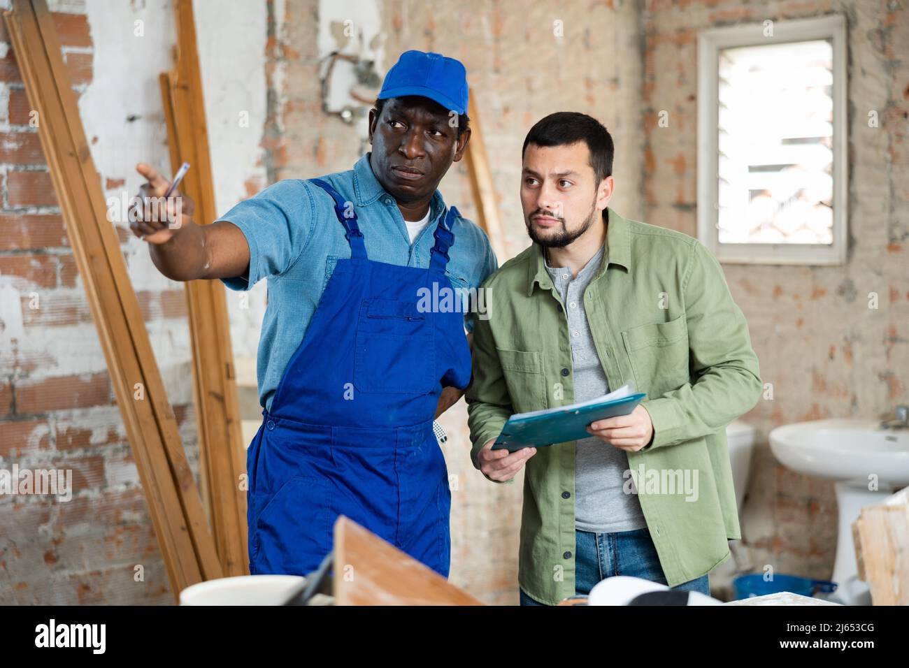 Builder having conversation with designer about working plan Stock Photo