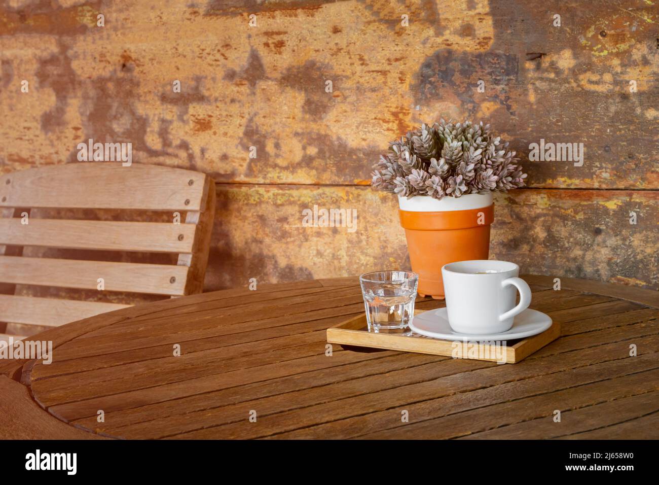 white coffee cup and glass of water on vintage wooden table and flower pot Stock Photo