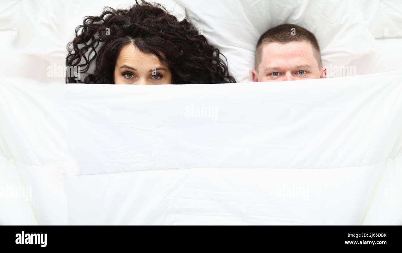 Man and woman covering with white blanket, awake couple in bad Stock Photo