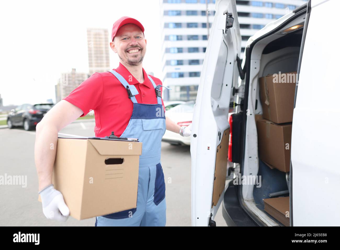 Smiling courier with parcels near delivery van Stock Photo