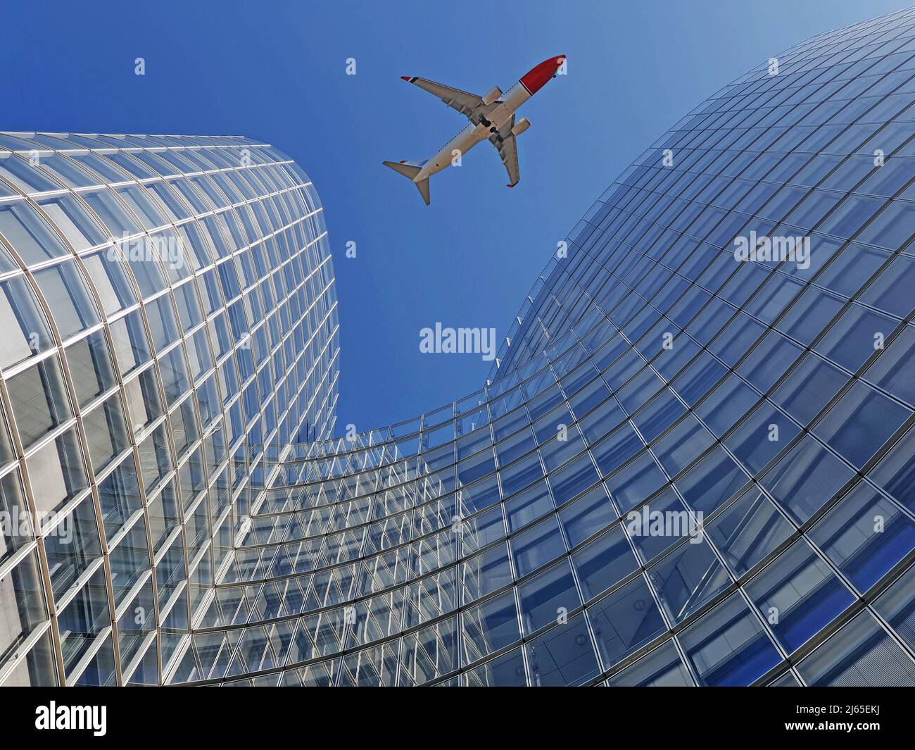 Plane flying over modern office glass skyscrapers Stock Photo