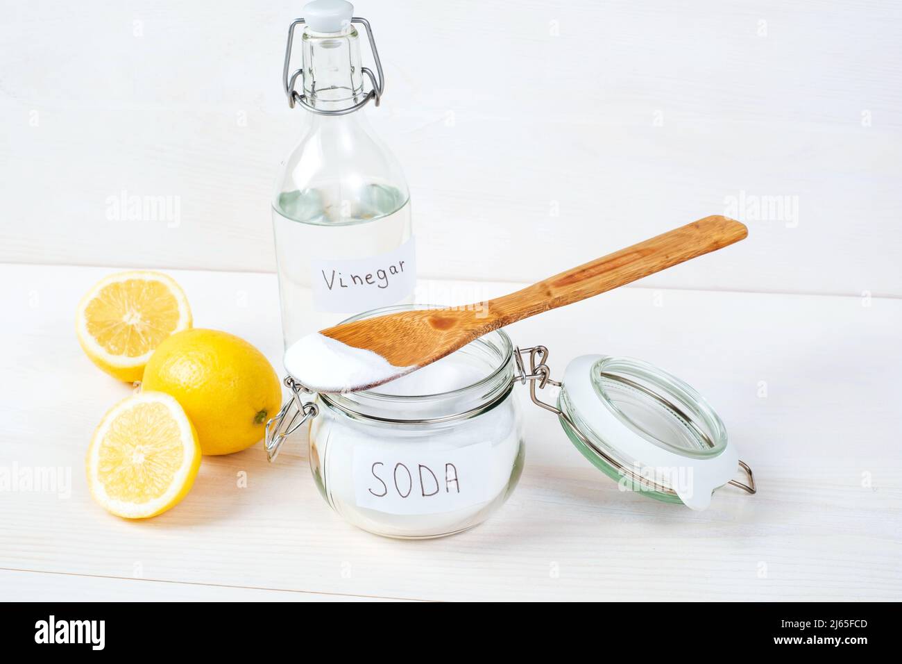 Baking soda in jar with a wooden spoon on top, vinegar, lemon on a