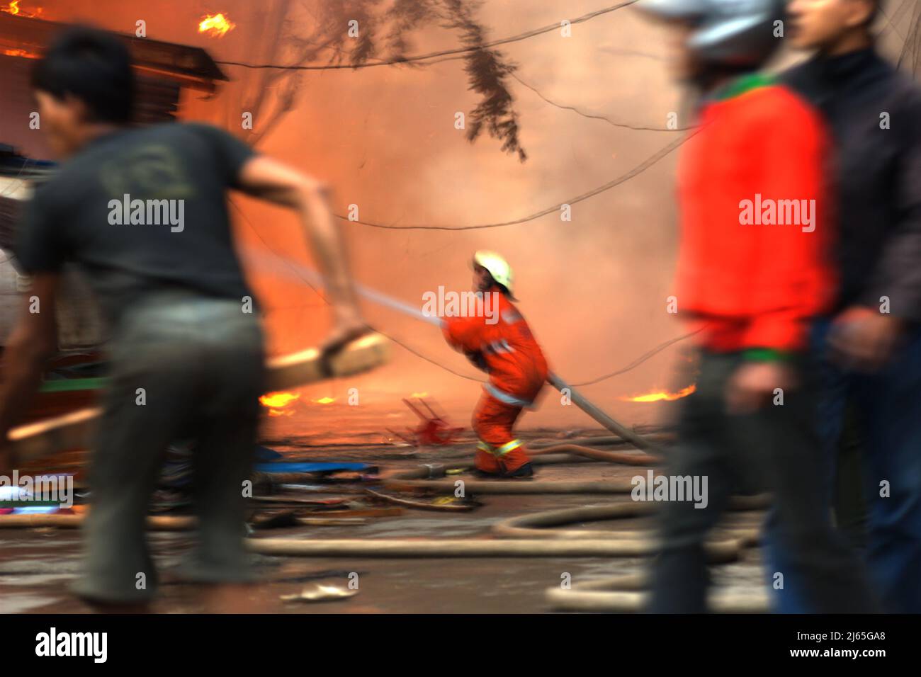 Firefighter and local people fighting a fire accident in a dense neighborhood in Penjaringan, North Jakarta, Jakarta, Indonesia. Stock Photo