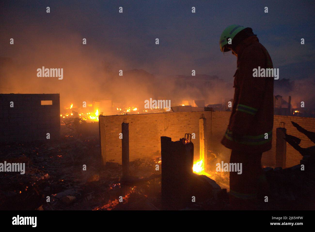 A firefighter taking a break from firefighting after a fire accident burned down hundreds of houses in a dense neighborhood in Penjaringan, North Jakarta, Jakarta, Indonesia. Stock Photo
