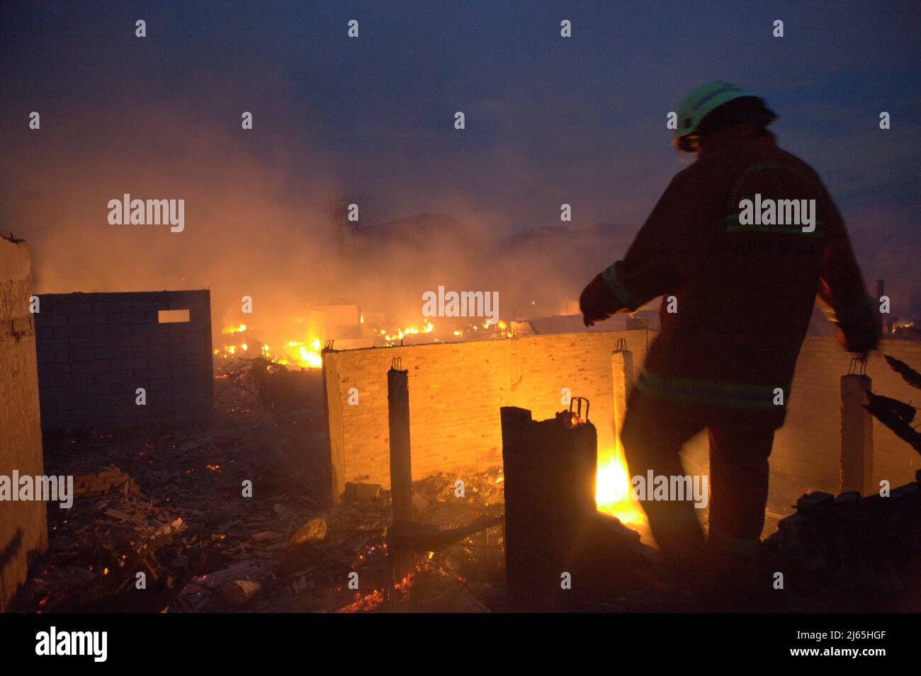 A firefighter walking toward the ruins and debris after a fire accident burned down hundreds of houses in a dense neighborhood in Penjaringan, North Jakarta, Jakarta, Indonesia. Stock Photo