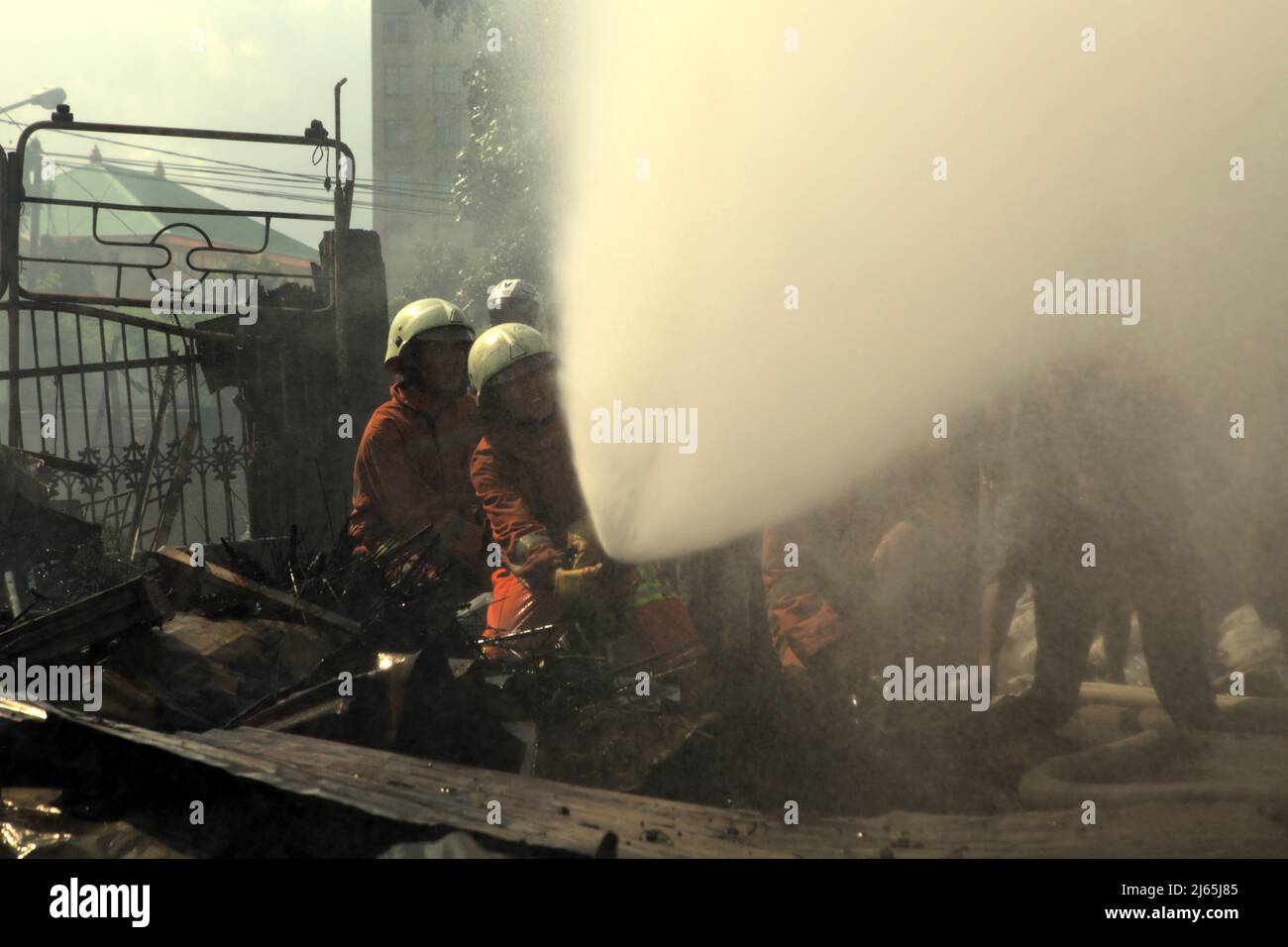 Members of Jakarta firefighting squad performing the cooling phase after a fire accident burned down storage buildings of a home industry in Kebayoran Lama, South Jakarta, Jakarta, Indonesia. Stock Photo