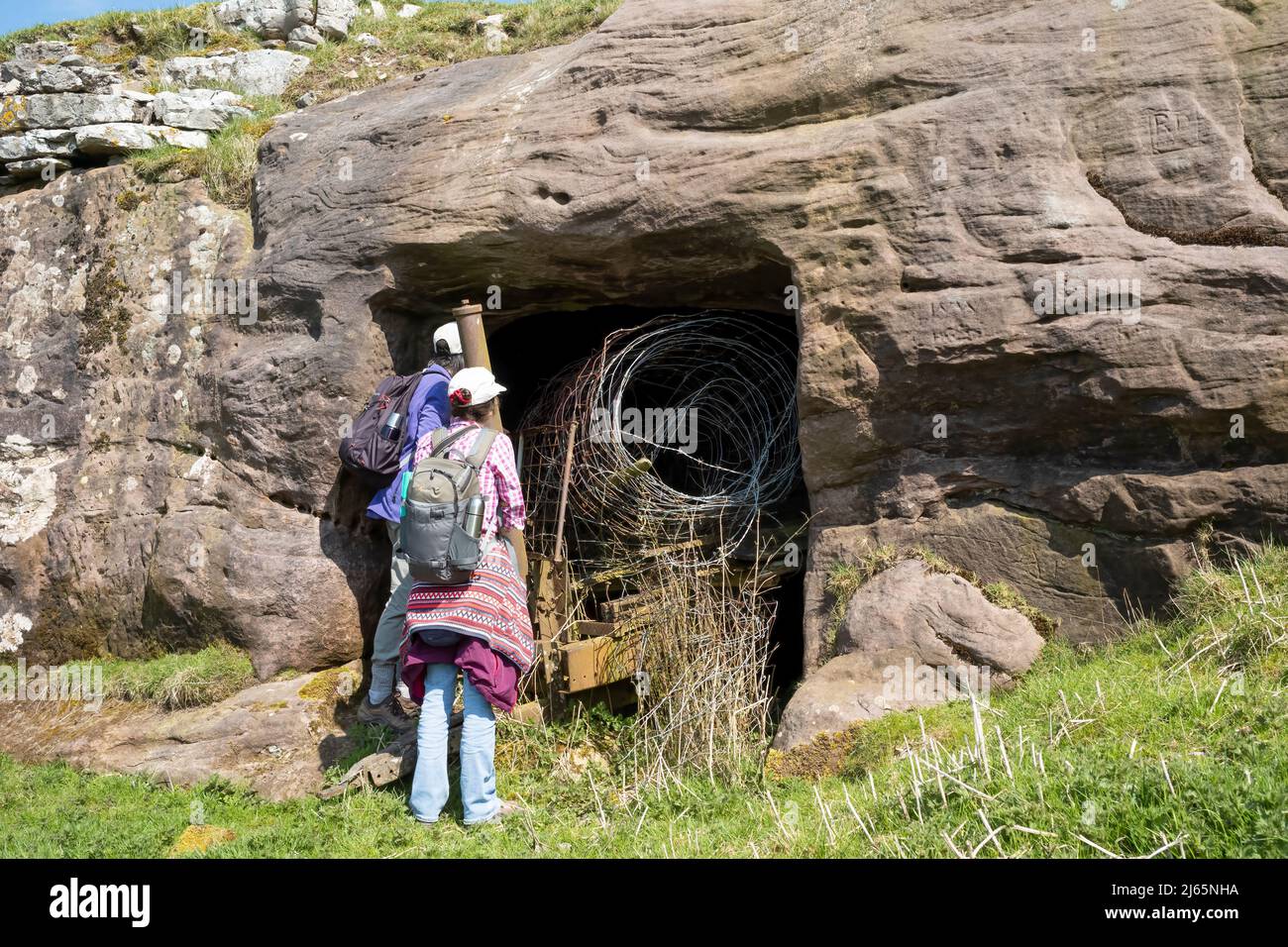 Walkers inspecting the entrance to an 18th century carved byre above Ravenstonedale, Upper Lune Valley, Yorkshire Dales National Park, UK Stock Photo