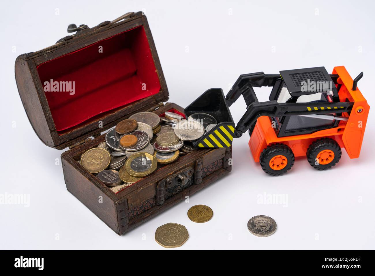 a mini loader loads coins into a chest on a white background Stock Photo