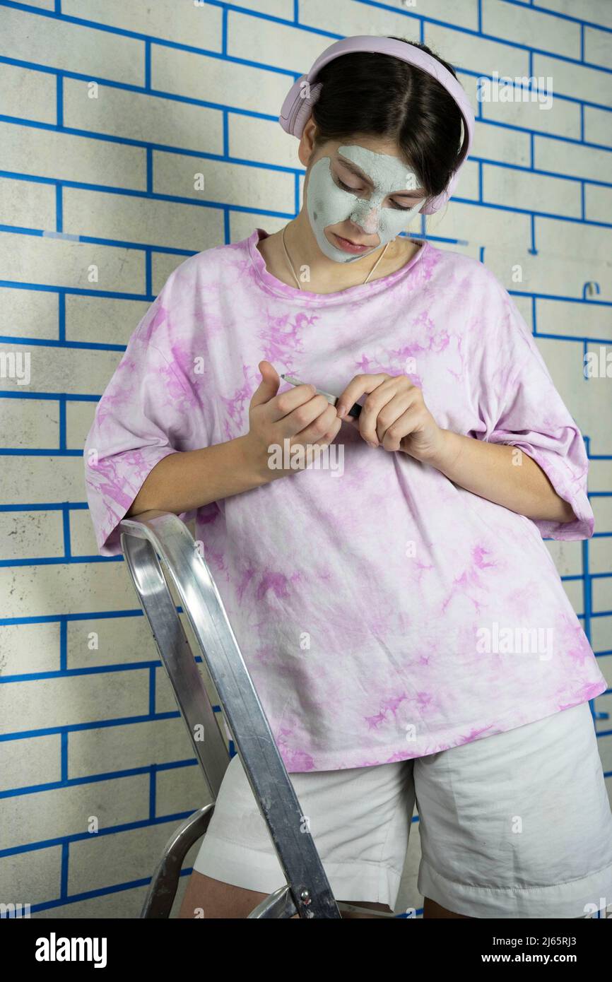 teenage girl takes care of her face by applying a cosmetic mask Stock Photo