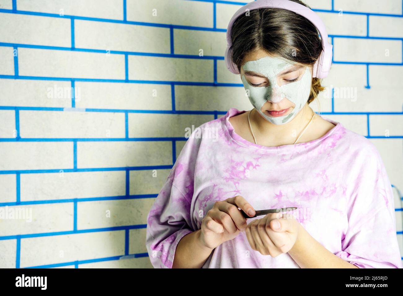 teenage girl takes care of her face by applying a cosmetic mask Stock Photo