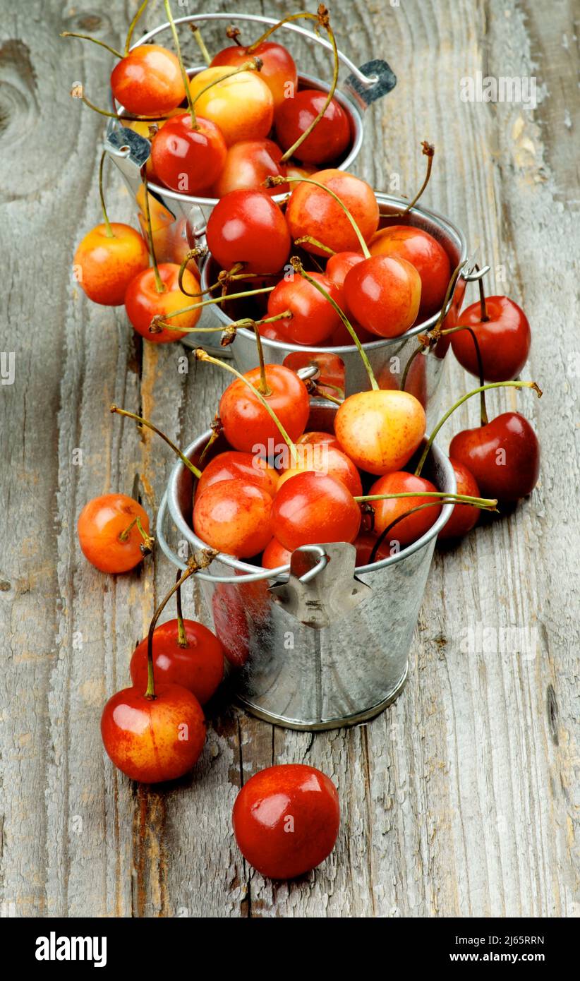 Arrangement of Tin Buckets Full of Ripe Sweet Maraschino Cherries on Rustic Wooden background Stock Photo