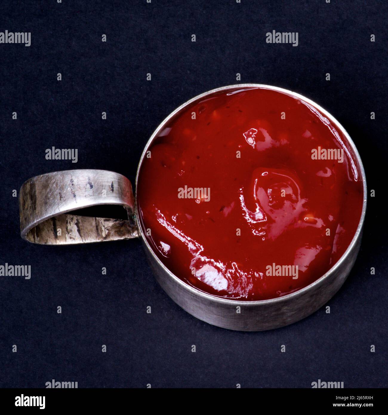 Homemade Tomato Ketchup in Vintage Tin Gravy Boat closeup on Black background Stock Photo