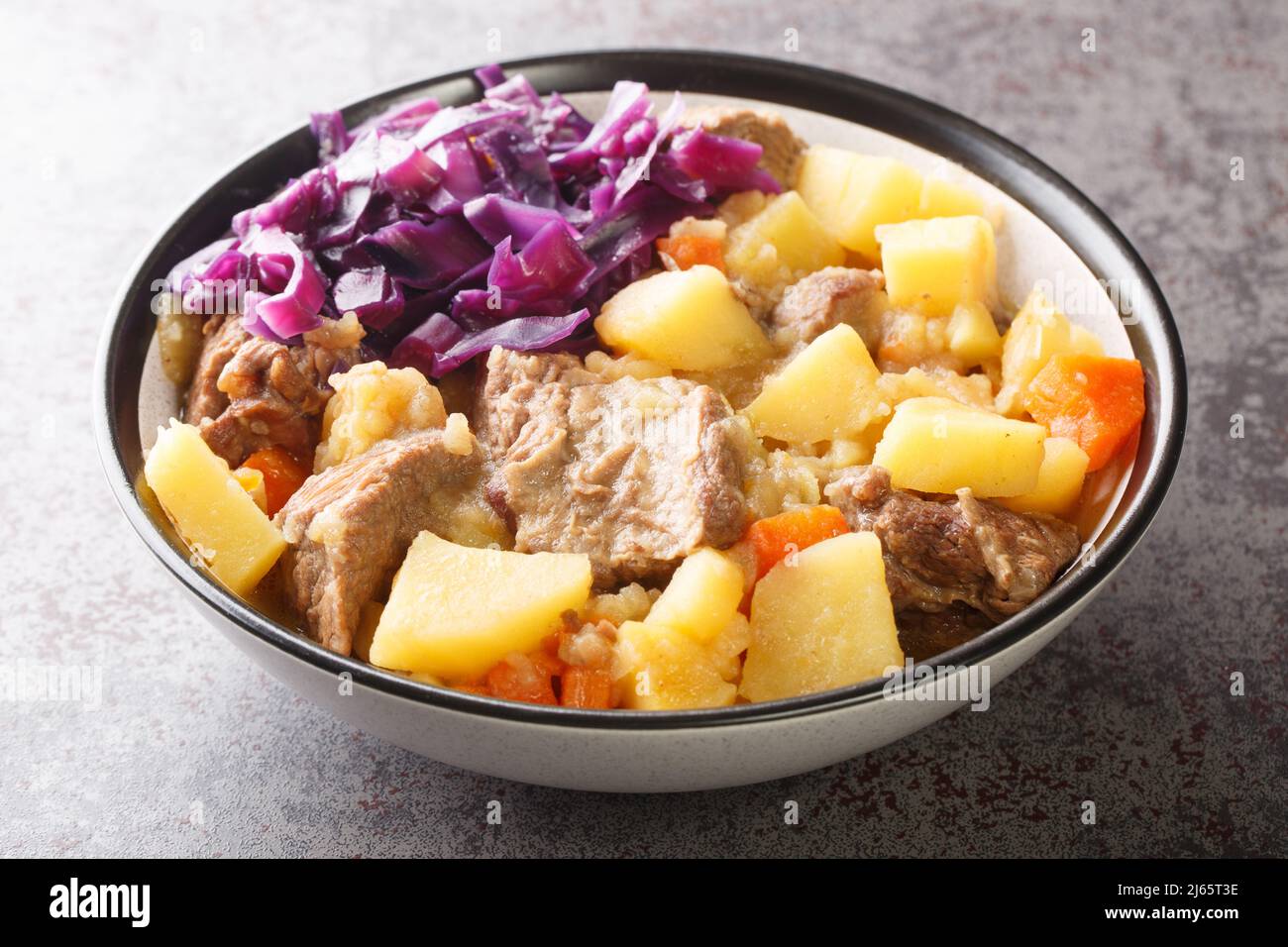 Scouse is a stew with meat and vegetables served with pickled cabbage close-up in a plate on the table. Horizontal Stock Photo