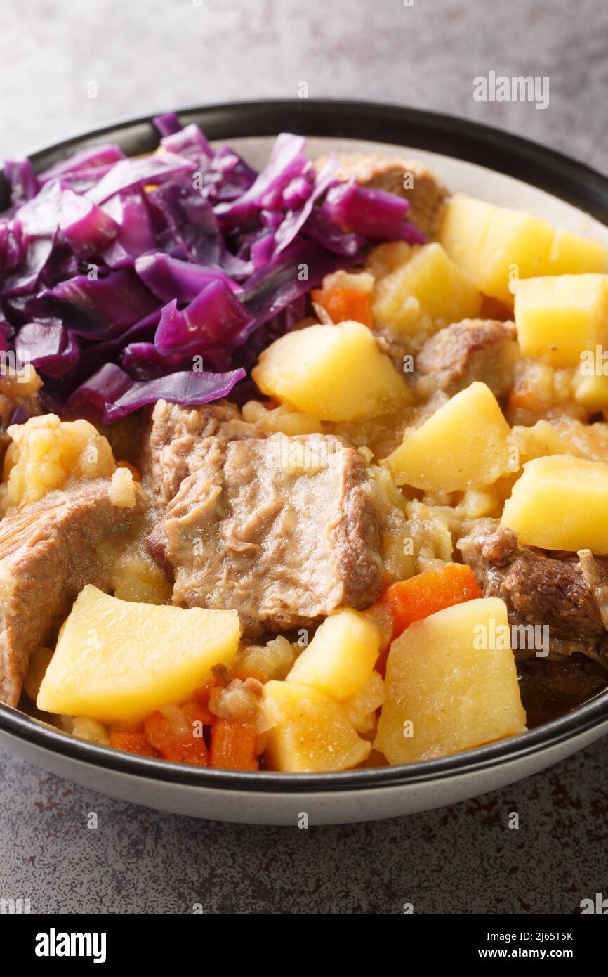 Scouse is a slow lamb stew with potatoes, turnips, onions and carrots close-up in a plate on the table. Vertical Stock Photo