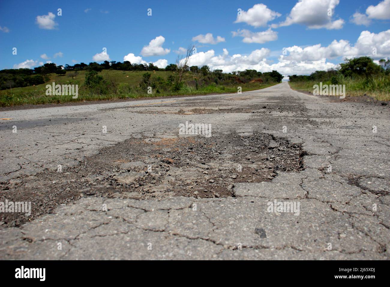 stretch of road with defective and spoiled asphalt, potholes and danger for traffic Stock Photo