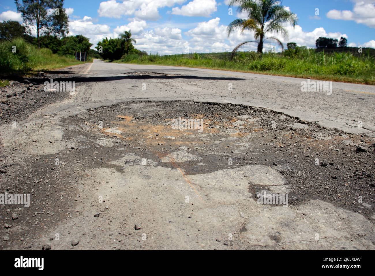 stretch of road with defective and spoiled asphalt, potholes and danger for traffic Stock Photo