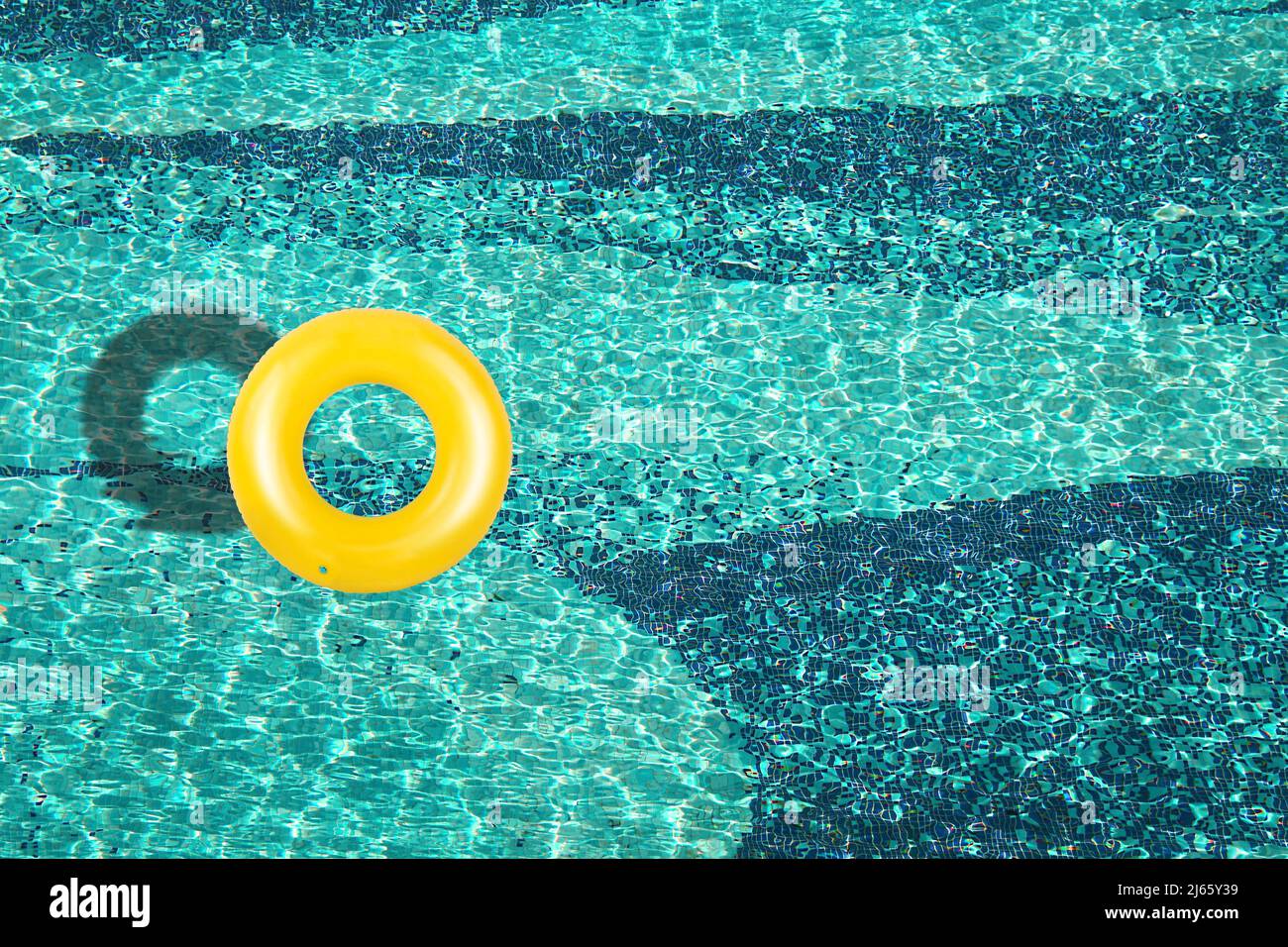 Aerial view of yellow ring float in a blue swimming pool under bright ...