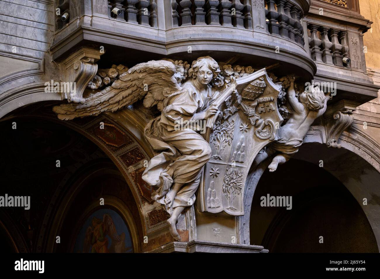 Rome. Italy. Basilica di Santa Maria del Popolo. Cantoria / organ loft, detail showing an angel supporting the coat of arms of Pope Alexander VII.  Ca Stock Photo