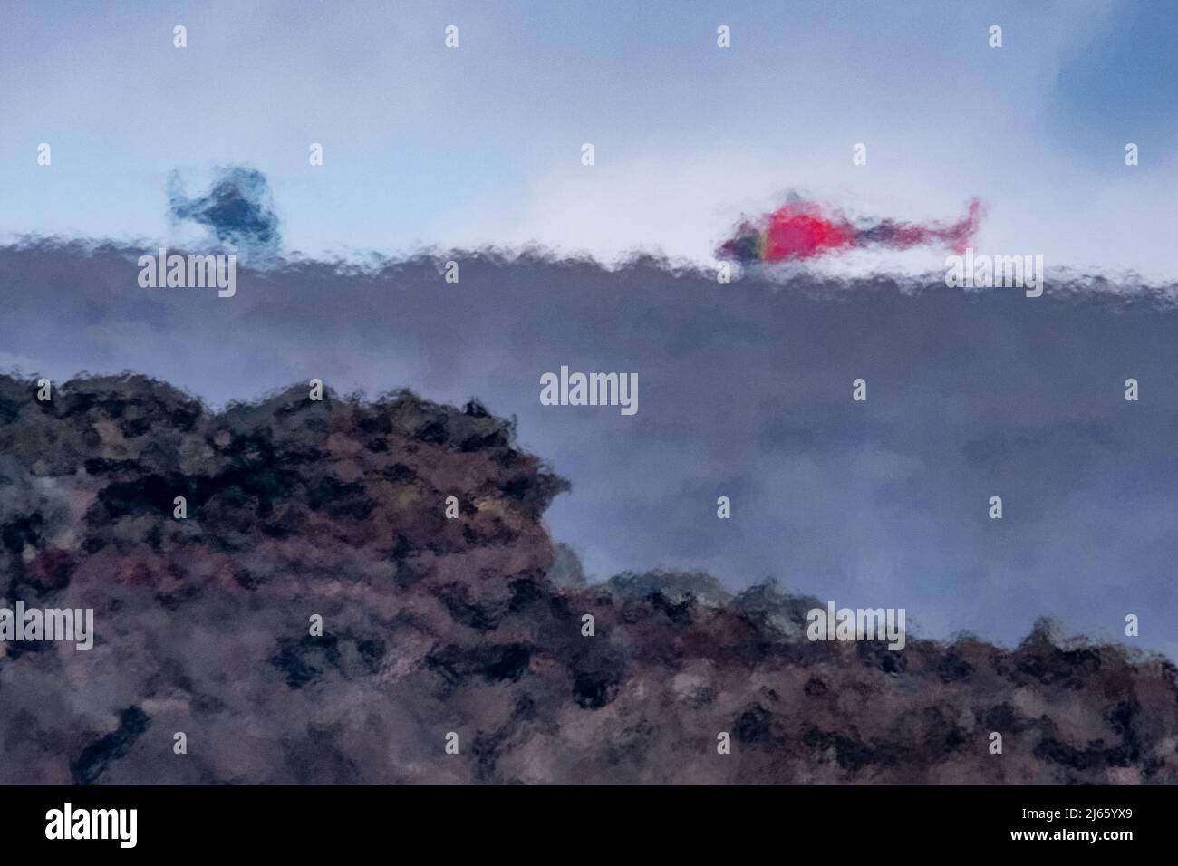 Zwei Hubschrauben stehen auf dem Bergrücken des Fagradalsfjall am Vulkanausbruch, die Luft flimmert durch die Hitze der Lavaströme. Stock Photo